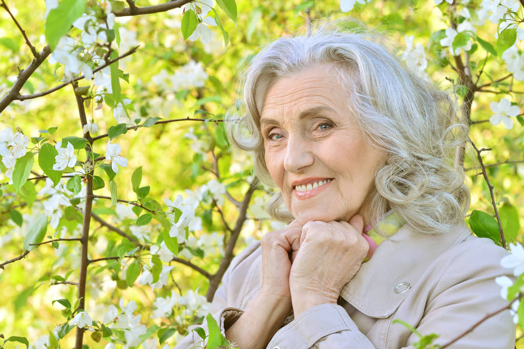 Seniorin nahe blühendem Baum - Foto, Bild