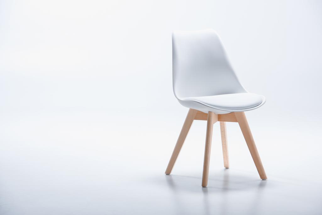 Stuhl mit weißer Platte und Holzbeinen - Foto, Bild