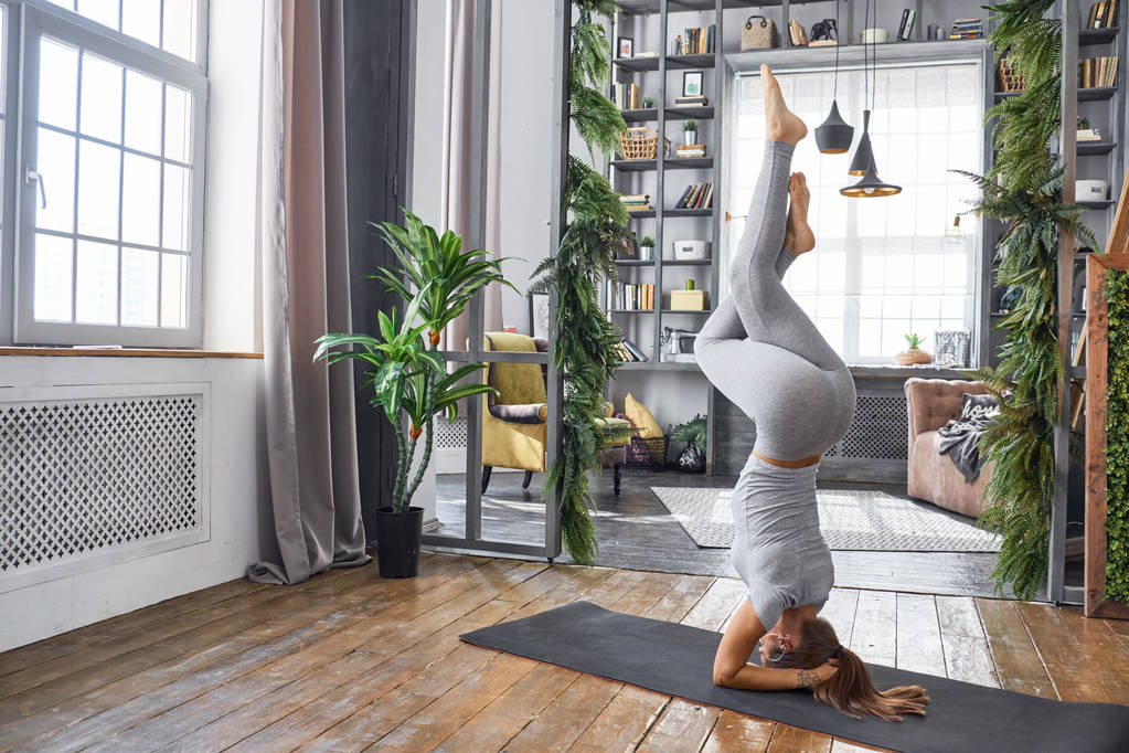 Frau praktiziert fortgeschrittenes Yoga im Wohnzimmer - Foto, Bild