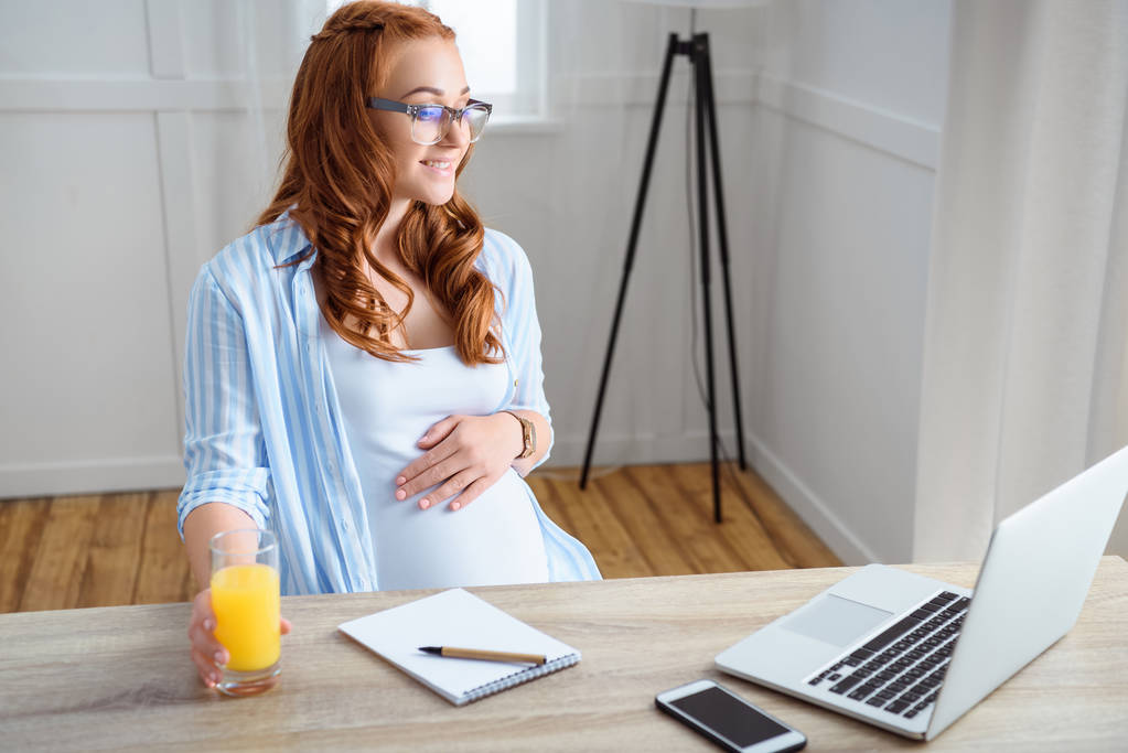 Mujer embarazada usando el ordenador portátil
 - Foto, Imagen