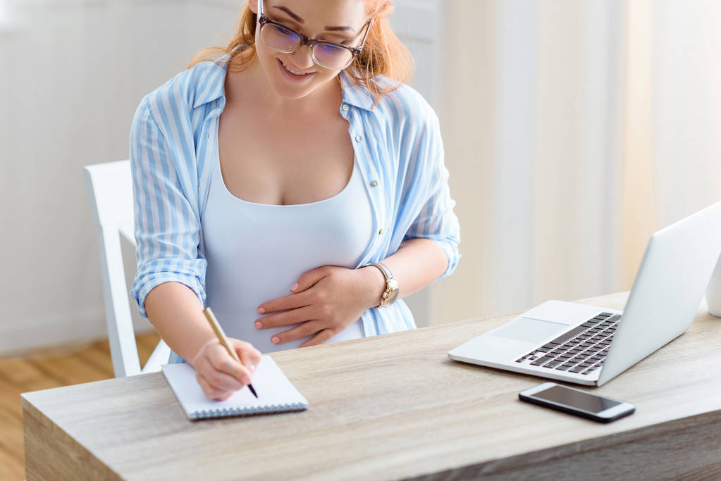 Femme enceinte écrivant dans un bloc-notes
  - Photo, image
