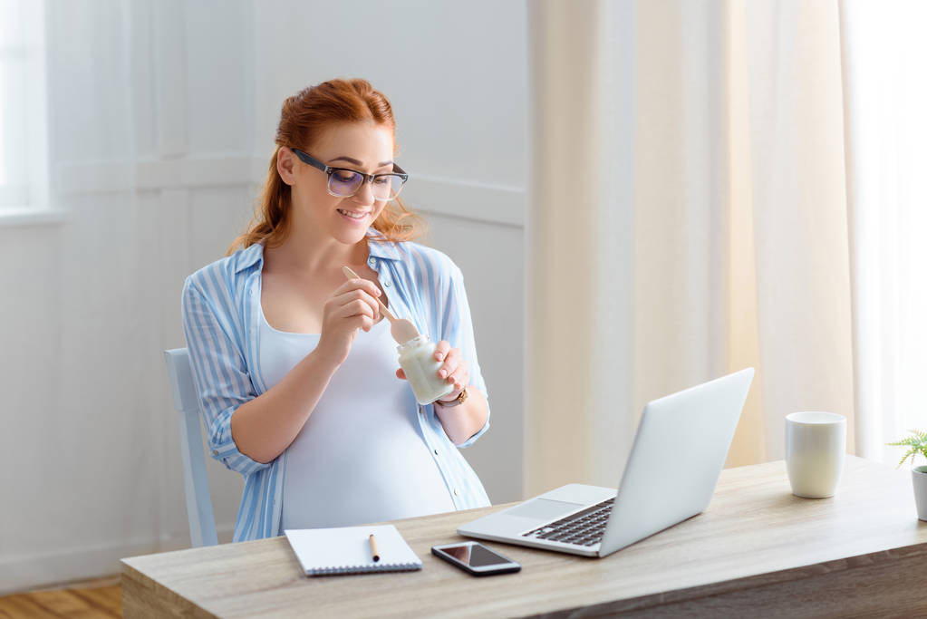 Raskaana oleva nainen syö jogurttia
 - Valokuva, kuva