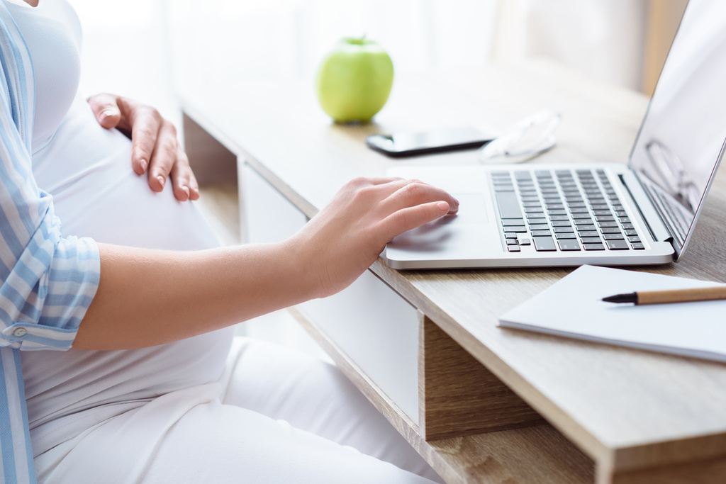 Donna incinta utilizzando il computer portatile
  - Foto, immagini