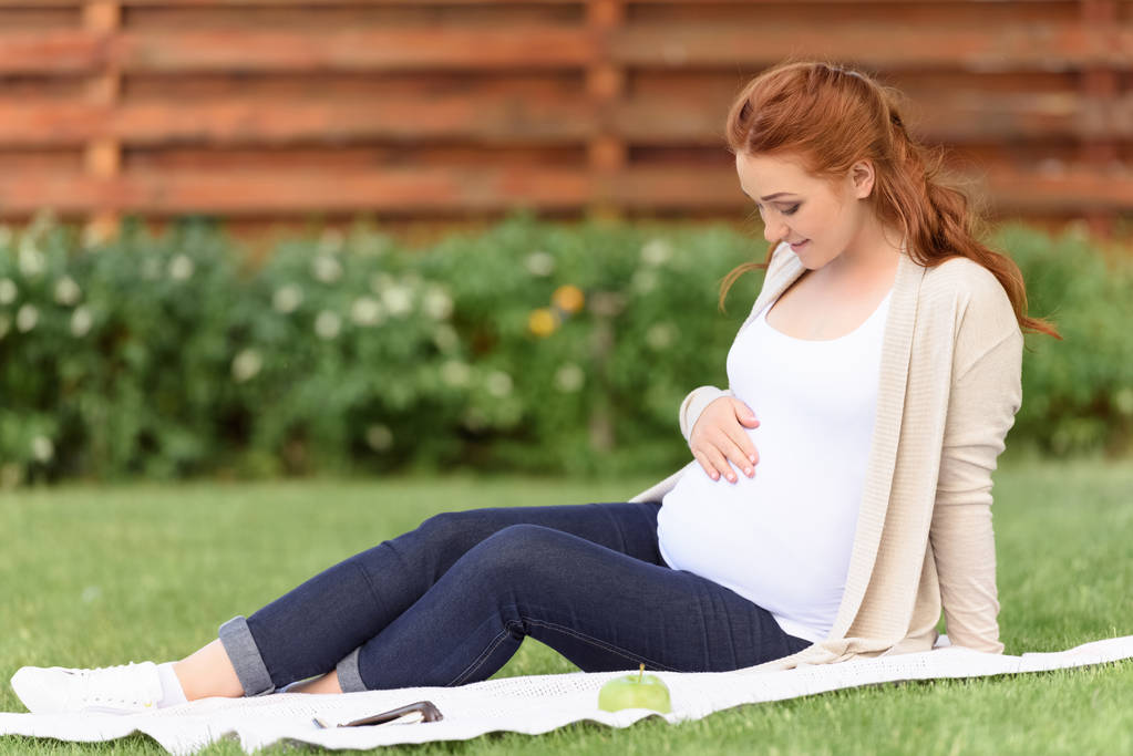 Çimenlikte oturan hamile kadın - Fotoğraf, Görsel