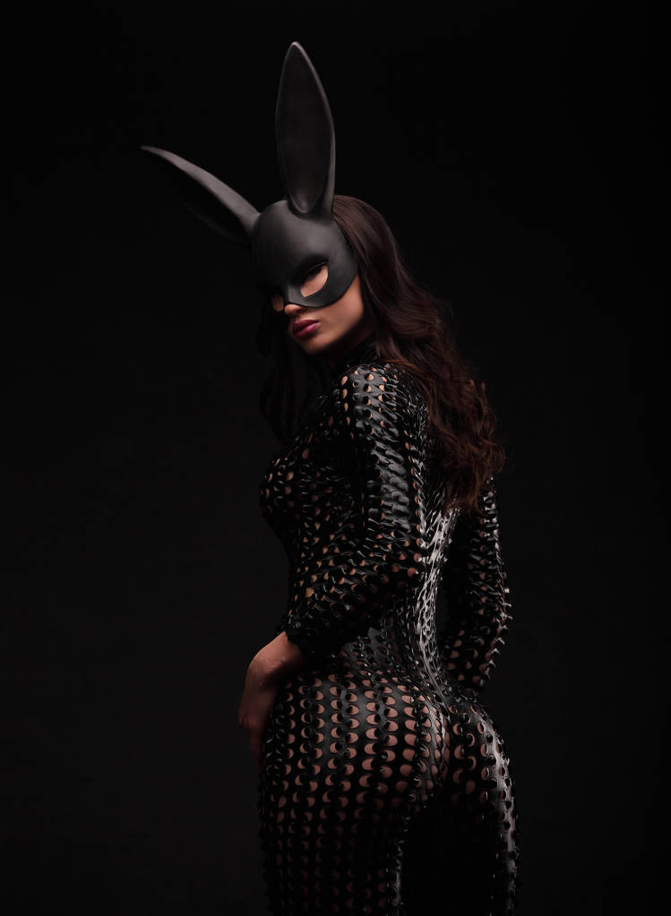 portrait of sexy brunette woman posing in rabbit black mask and bodysuit back shot - Photo, Image