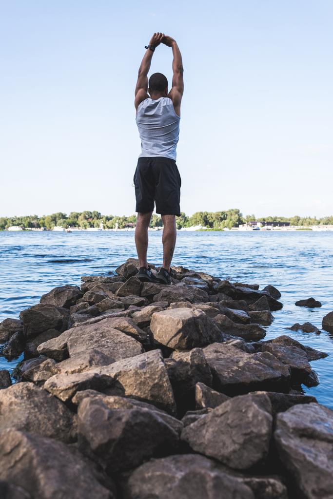 deportista afroamericano estirándose a orillas del río
   - Foto, Imagen