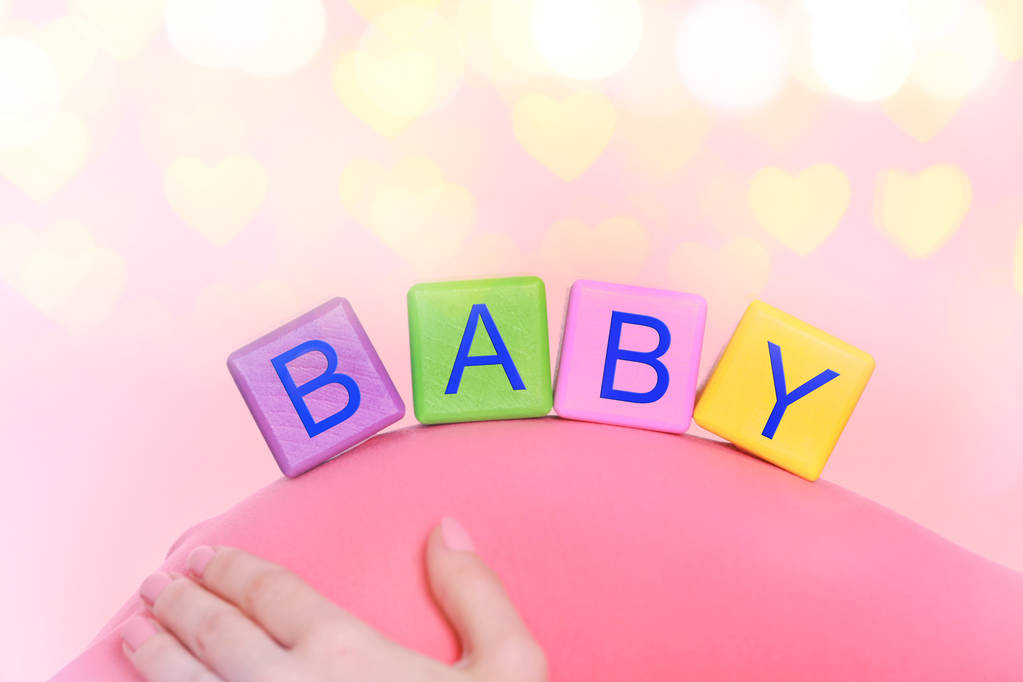 クリスマス ライトの背景に妊娠中の女性の腹部に赤ちゃん言葉でカラー キューブ - 写真・画像