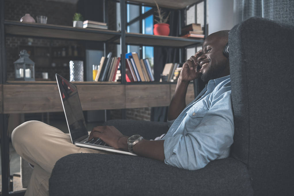 Афроамериканец использует ноутбук дома
 - Фото, изображение