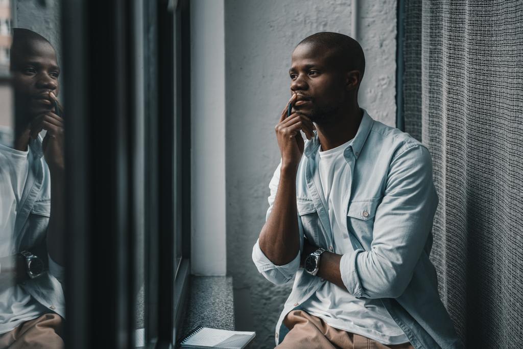 Αφρικανική αμερικανική άνθρωπος που ψάχνει στο παράθυρο - Φωτογραφία, εικόνα