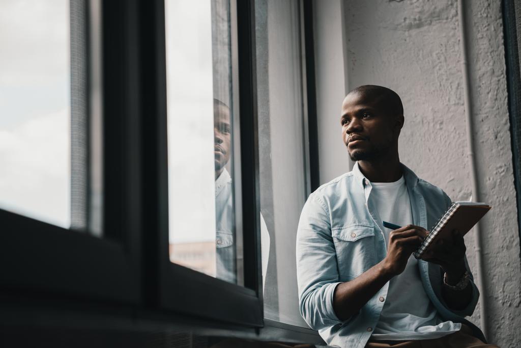 Afro-Amerikaanse man venster kijken - Foto, afbeelding