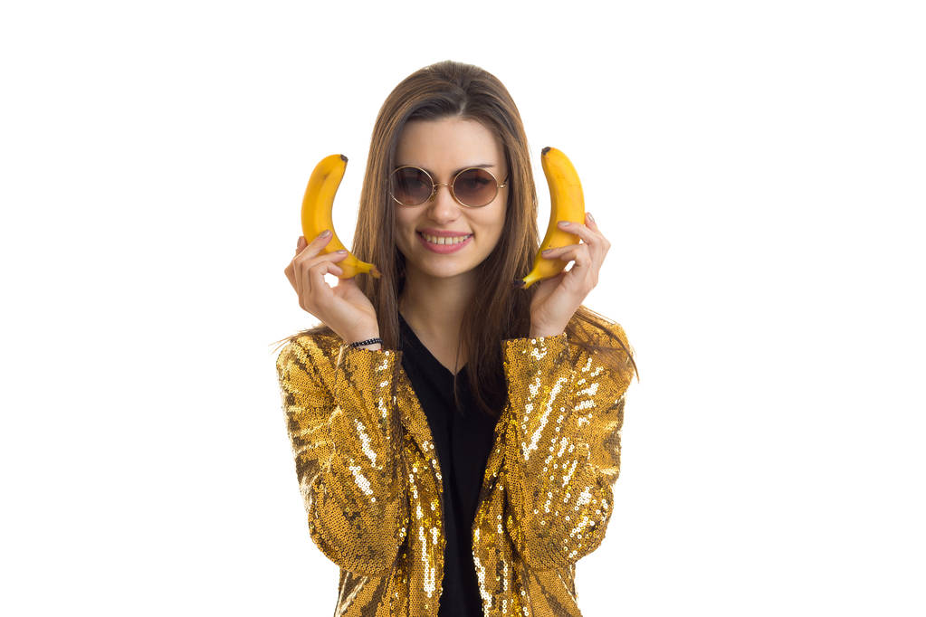 Cheerful stylish woman in golden jacket with bananas - Valokuva, kuva