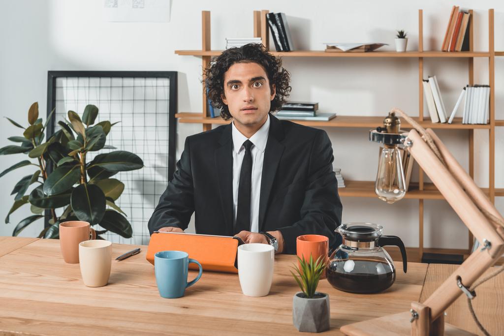 бизнесмен с планшетом и кофейными чашками на рабочем месте
 - Фото, изображение
