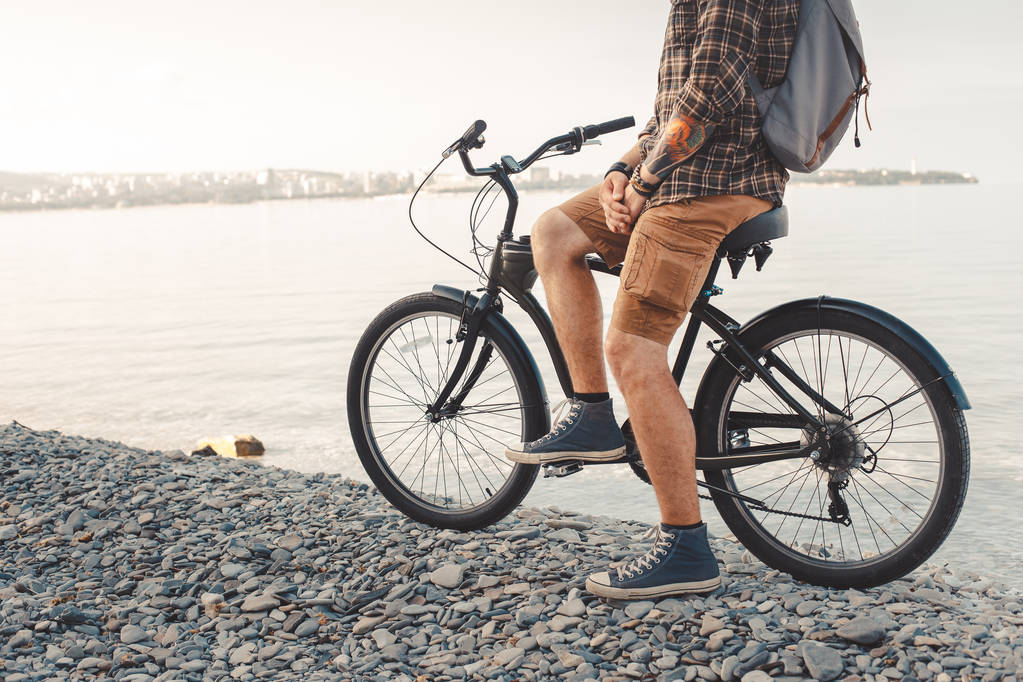 Jonge wielrenner met rugzak met fiets op de kust en genieten van uitzicht op zee zonsopgang rust reizen Wanderlust Concept - Foto, afbeelding