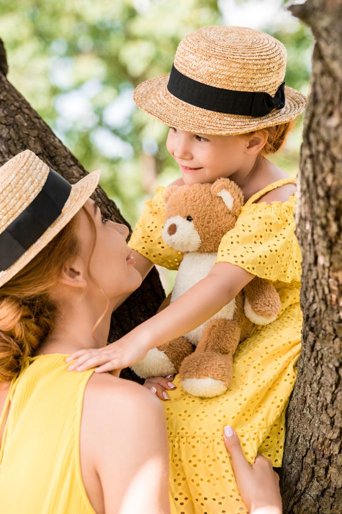 mother and daughter with teddy bear in park - Photo, Image