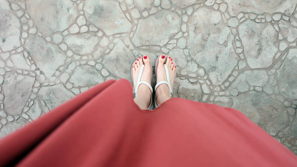 Gros plan sur les pieds de la fille portant des sandales et un ongle rouge sur la tuile
 - Photo, image
