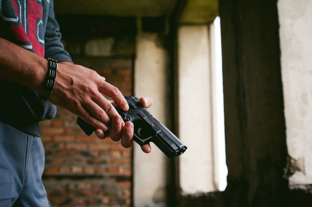 Hombre atlético en un pasamontañas, sostiene una pistola en su mano, es amenazado con disparar, apuntando
 - Foto, imagen