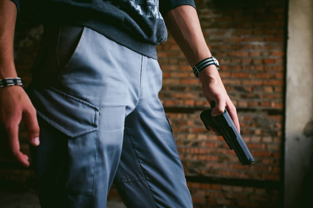 Atletische man in een balaclava, houdt een pistool in zijn hand, dreigt te schieten, die gericht zijn - Foto, afbeelding