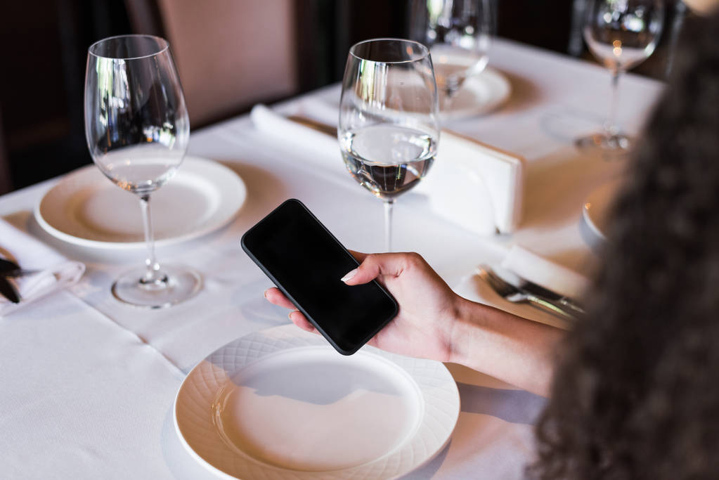 Nainen käyttää älypuhelinta ravintolassa
 - Valokuva, kuva