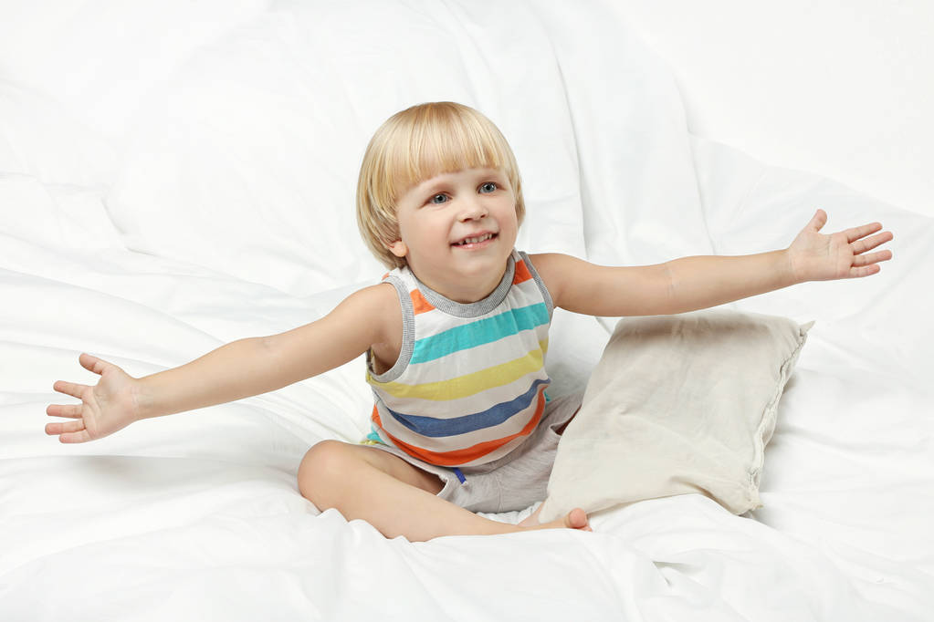 Μικρό αγόρι κάθεται στο κρεβάτι λευκό - Φωτογραφία, εικόνα