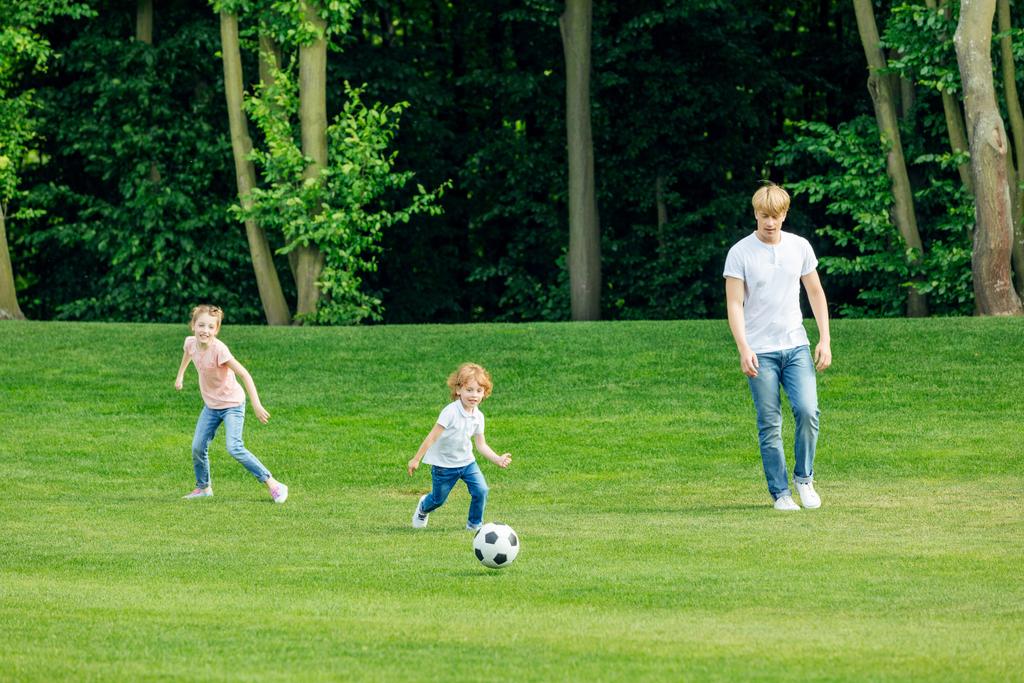 πατέρας με παιδιά παίζει ποδόσφαιρο στο πάρκο - Φωτογραφία, εικόνα