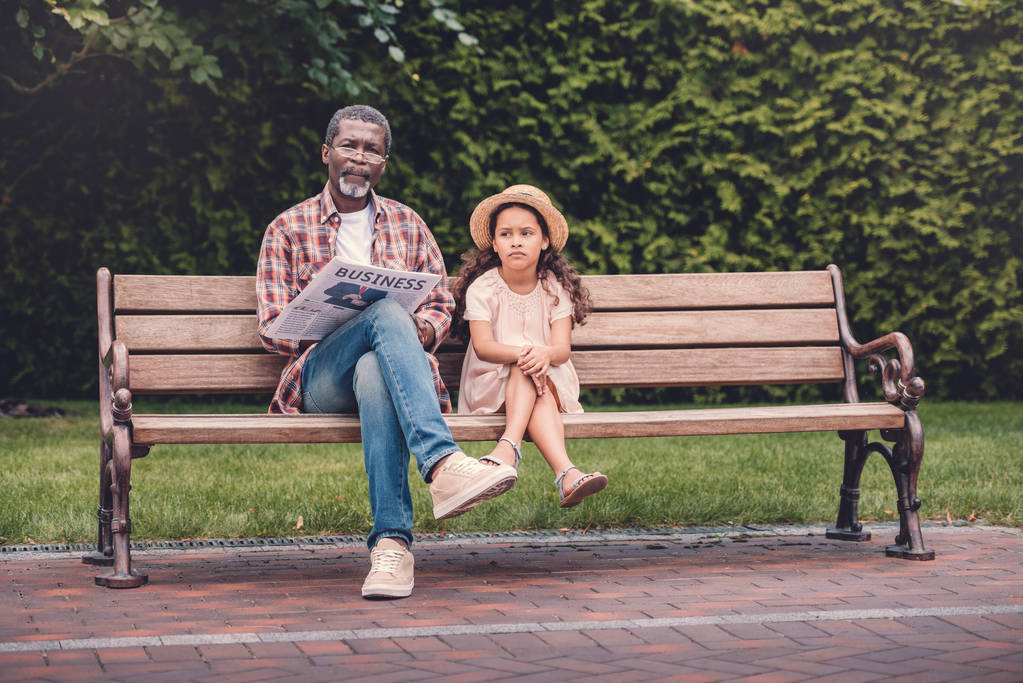 lapsenlapsi ja hänen isoisänsä istuu penkillä
 - Valokuva, kuva