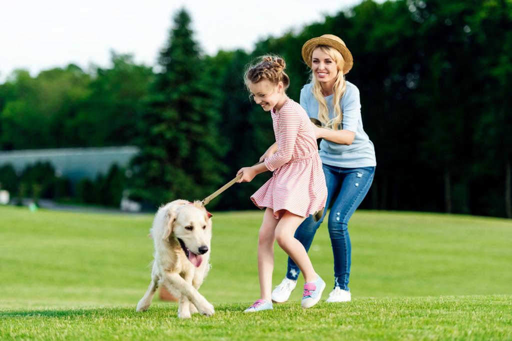 mother and daughter with dog in park - Photo, Image