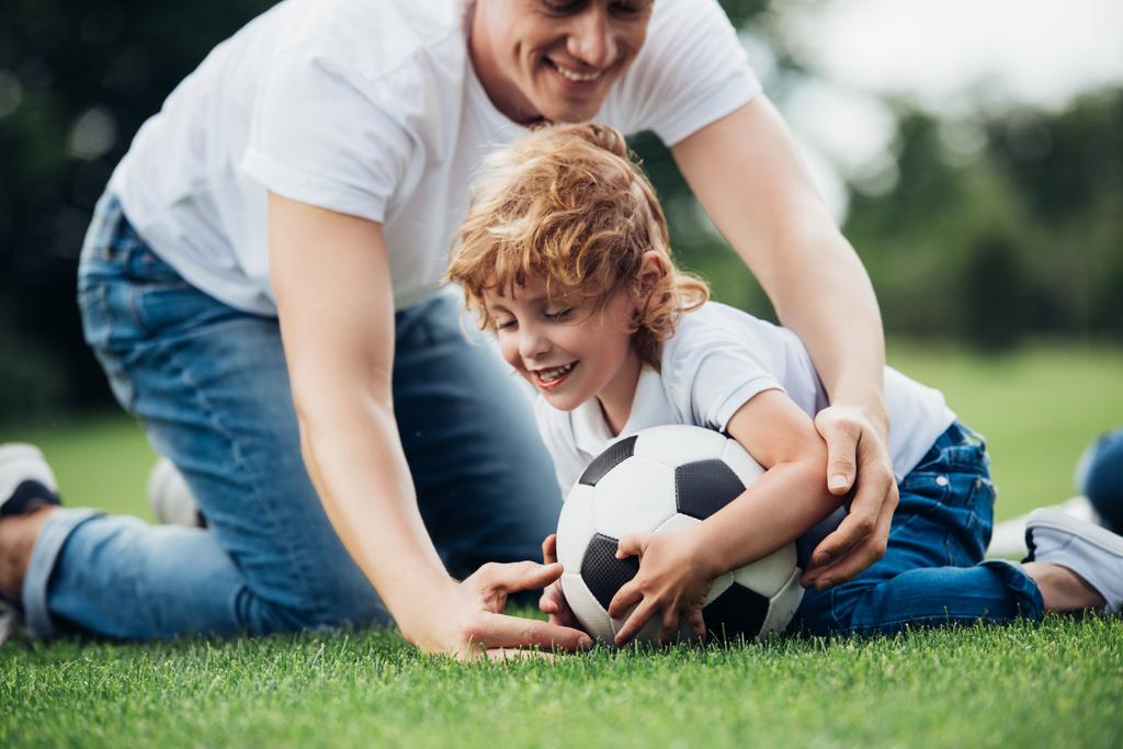 отец и сын играют в футбол в парке
 - Фото, изображение