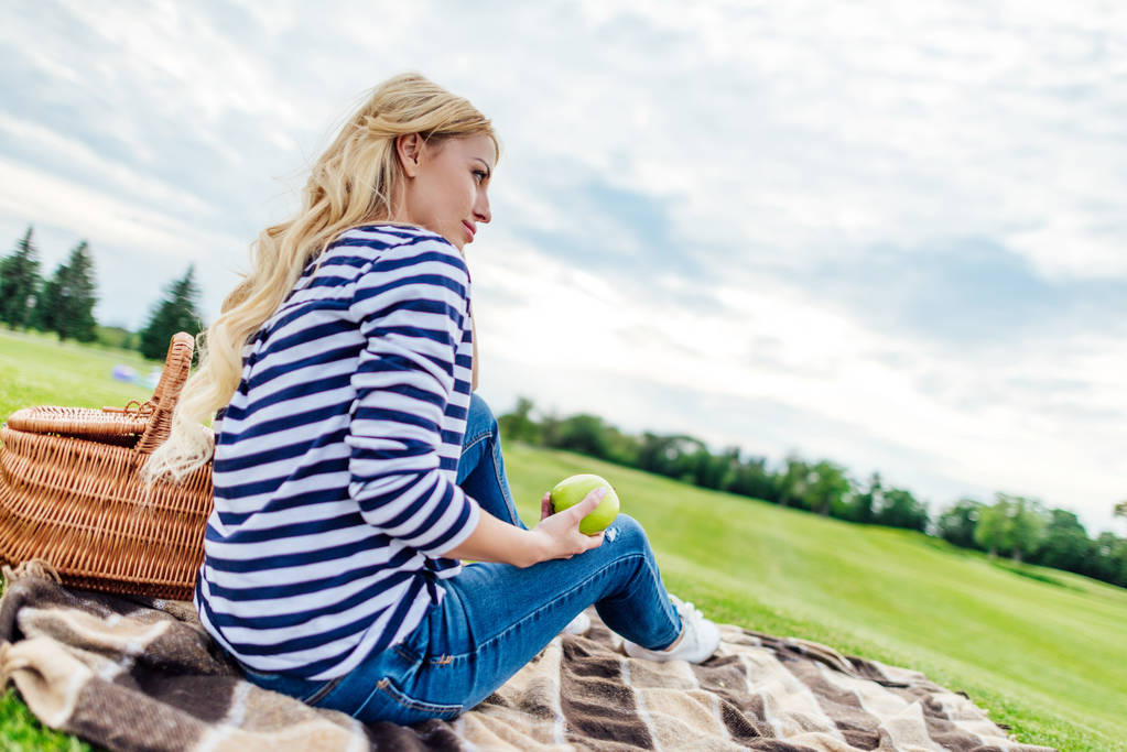 Nuori nainen omenan kanssa piknikillä
 - Valokuva, kuva