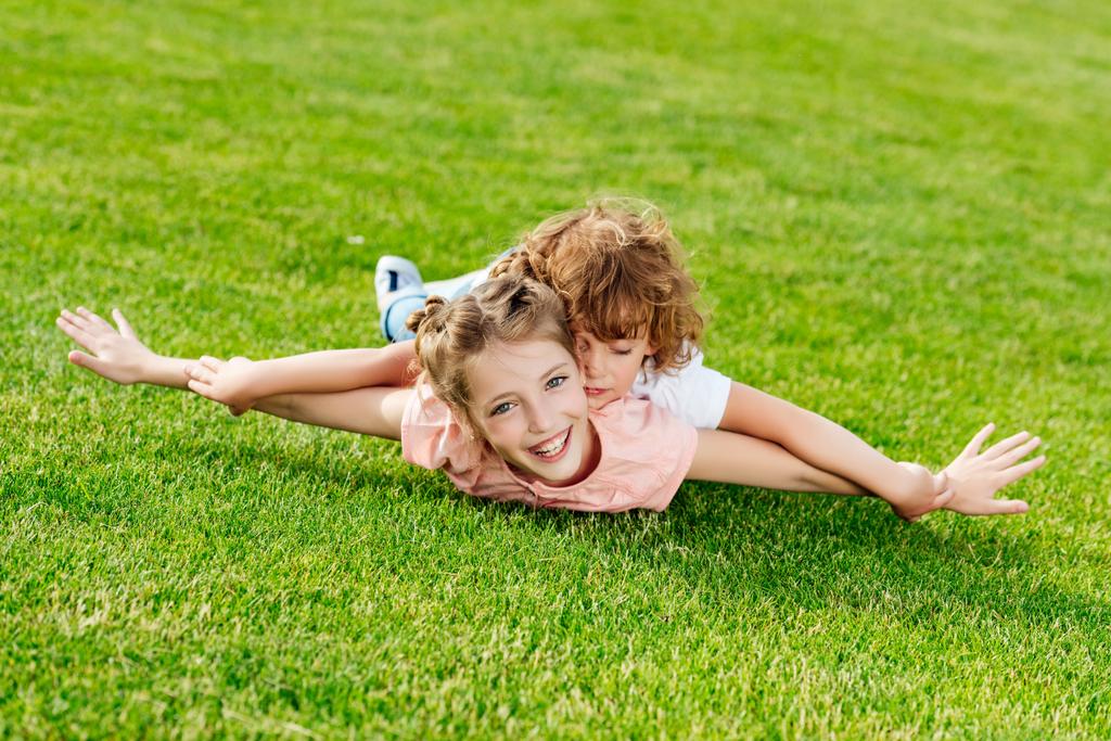 Broer en zus liggen op gras - Foto, afbeelding