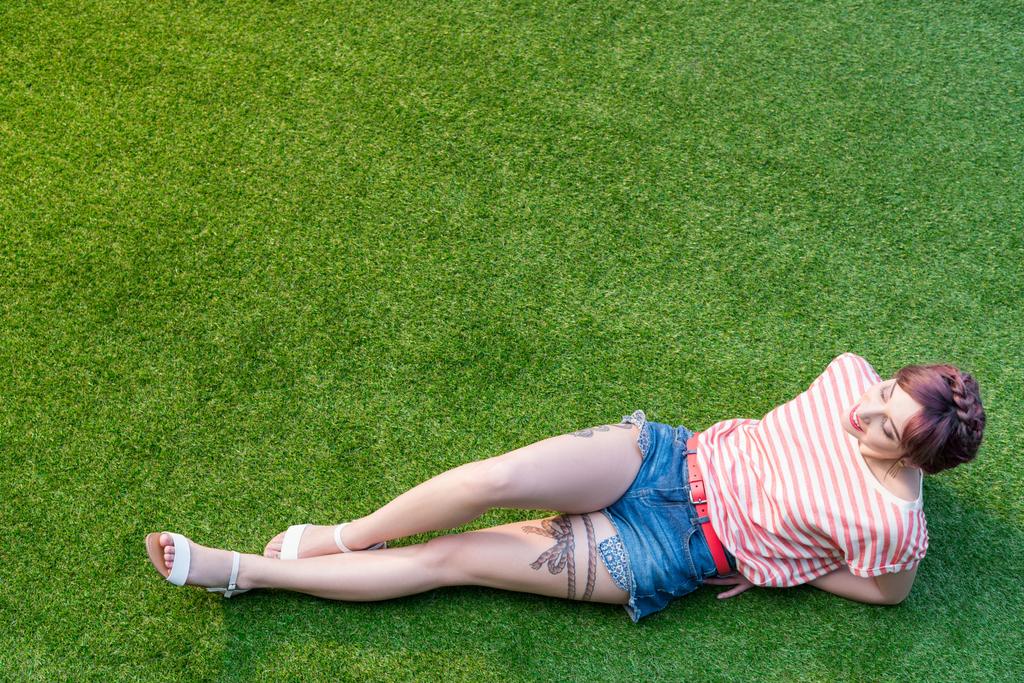 Молода жінка відпочиває на траві
 - Фото, зображення