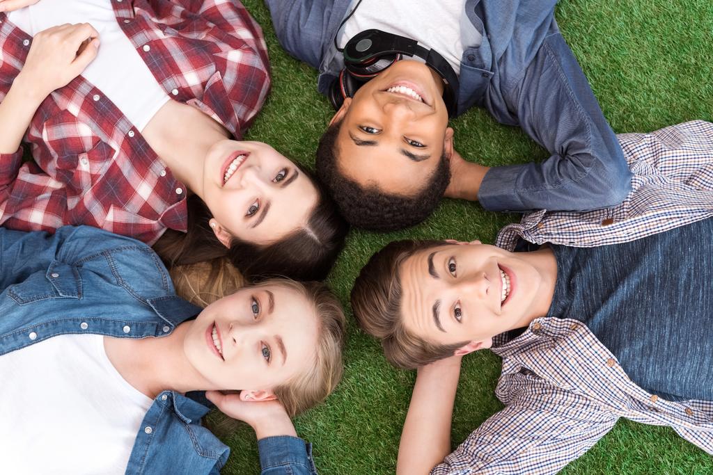 multiethnic teenagers lying on green lawn - Photo, Image