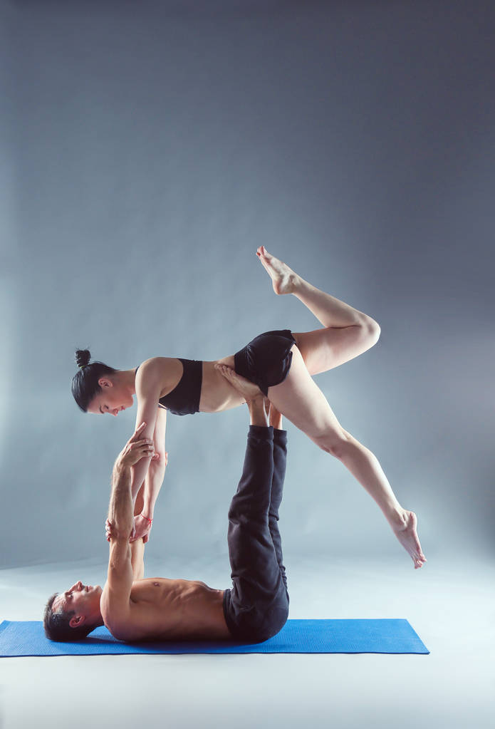 Casal jovem praticando acro ioga no tapete em estúdio juntos. Acroyoga. Um par de ioga. Parceiro ioga
. - Foto, Imagem