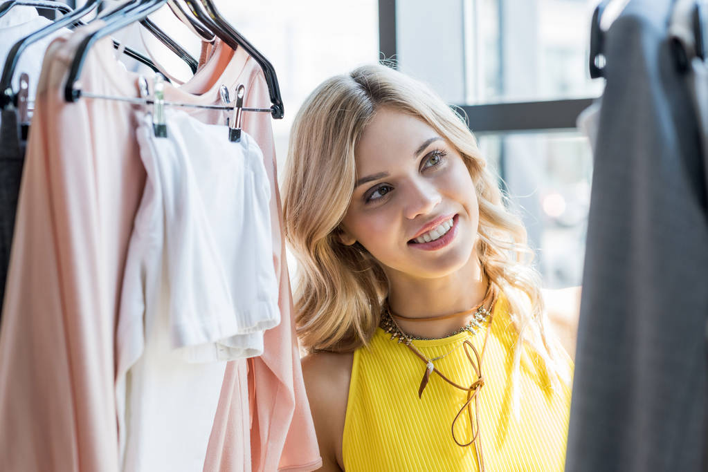 beautiful blonde woman choosing clothes in store - Photo, Image