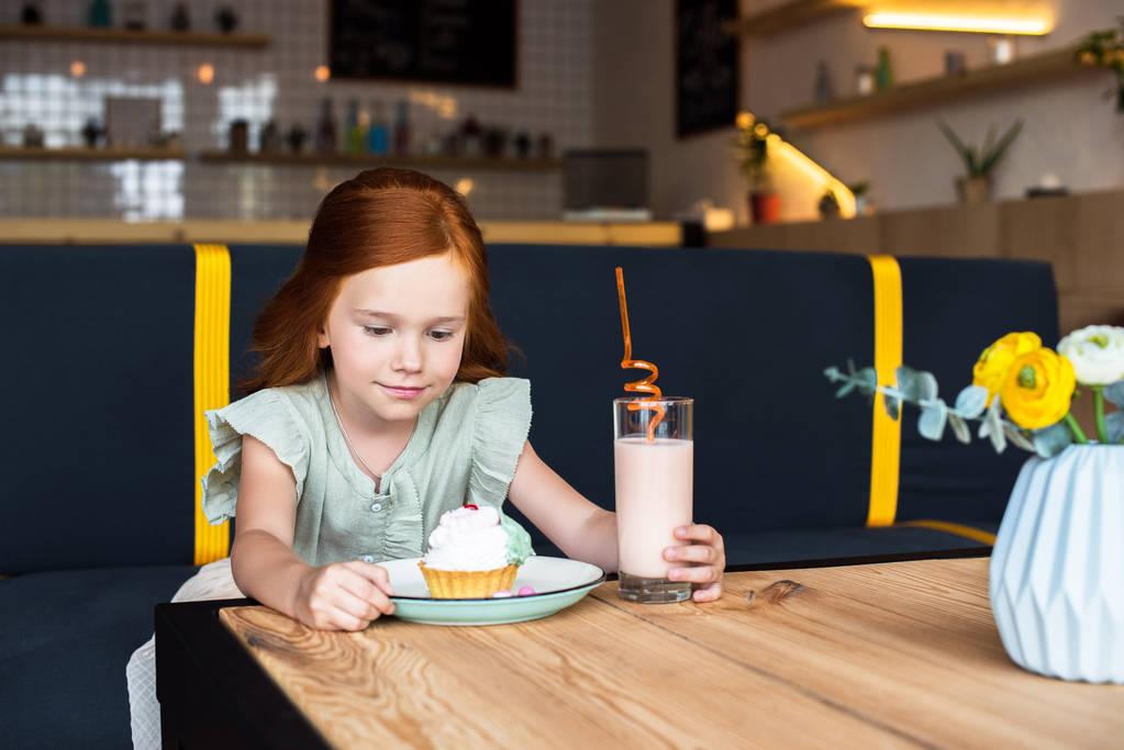 Tyttö syö cupcake kahvilassa
 - Valokuva, kuva