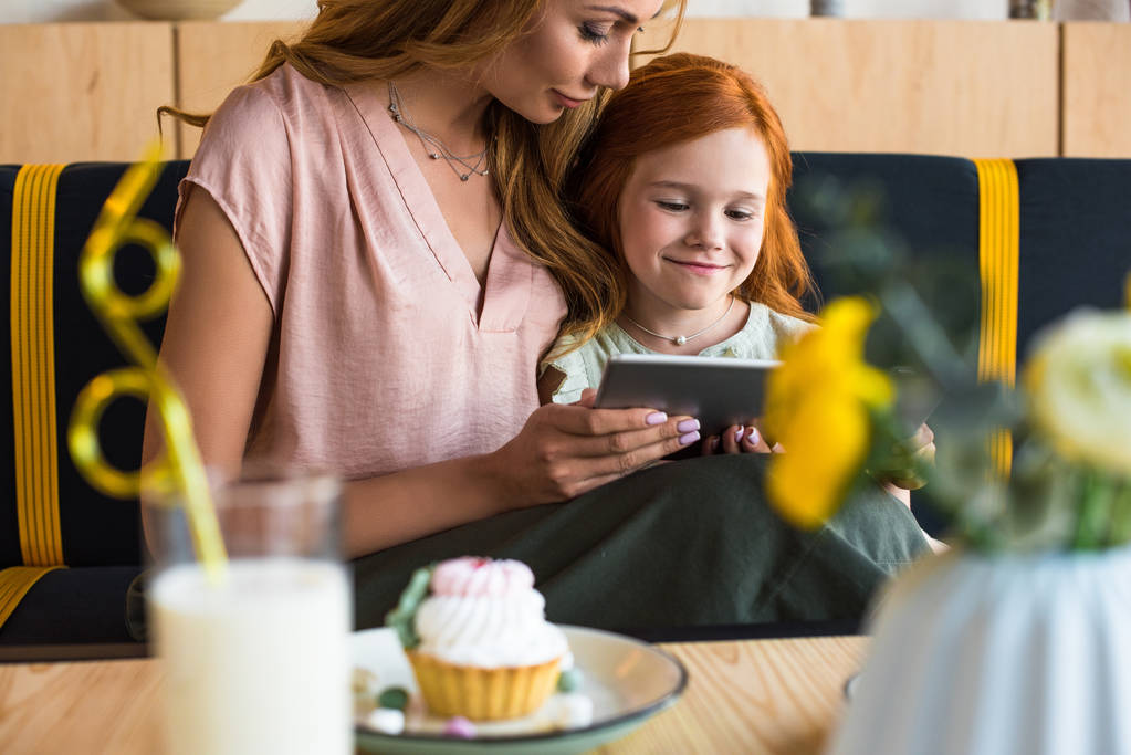 moeder en dochter met digitale tablet in café - Foto, afbeelding
