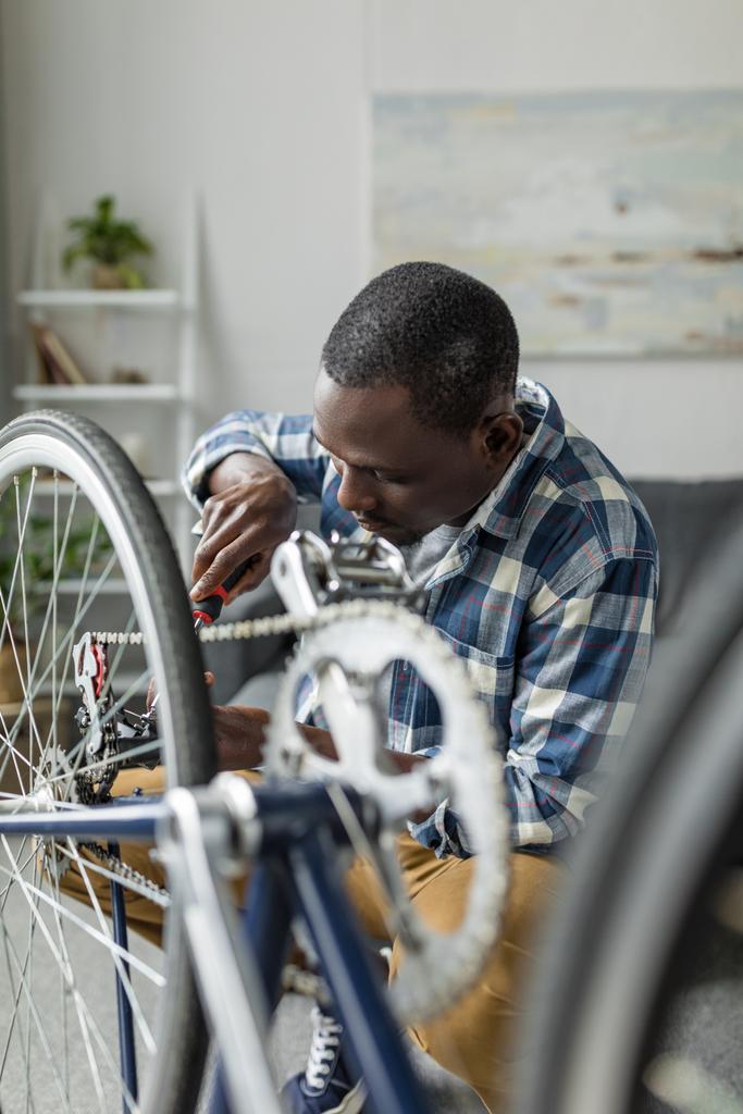 afro hombre reparando bicicleta en casa
 - Foto, imagen