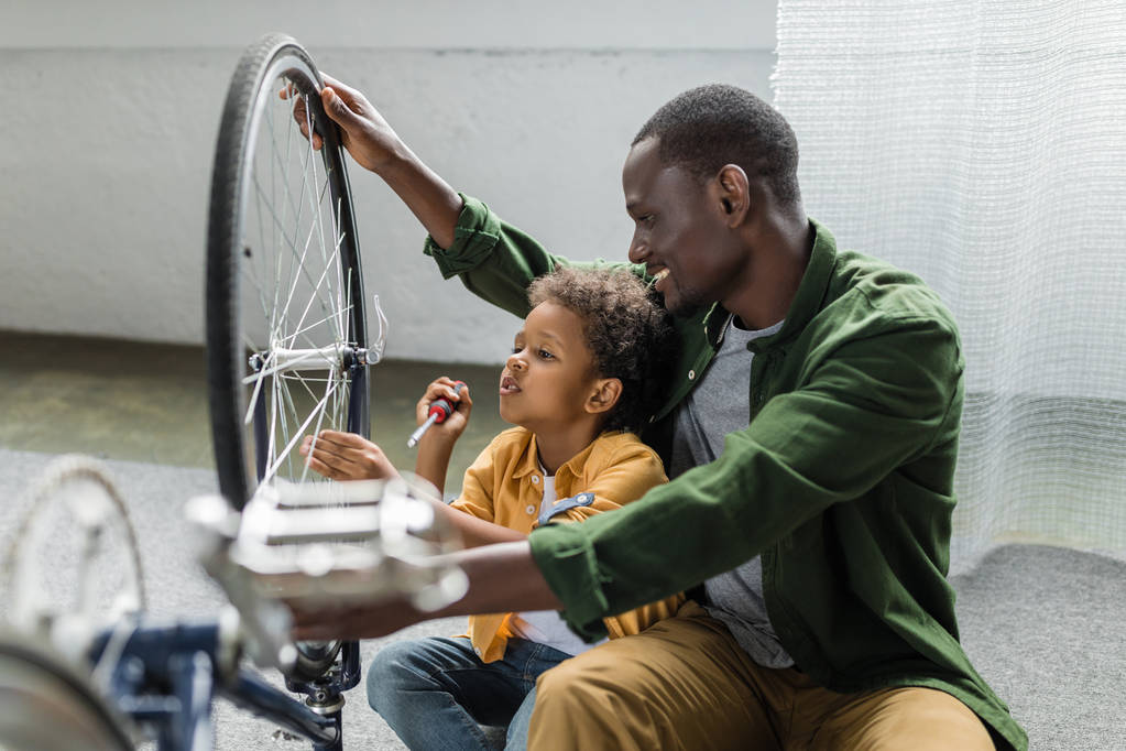афро батько і син ремонтують велосипед
 - Фото, зображення