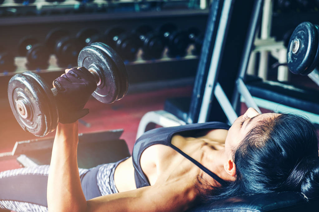 Asian sports woman doing exercises with dumbbell weights in gym - Photo, Image