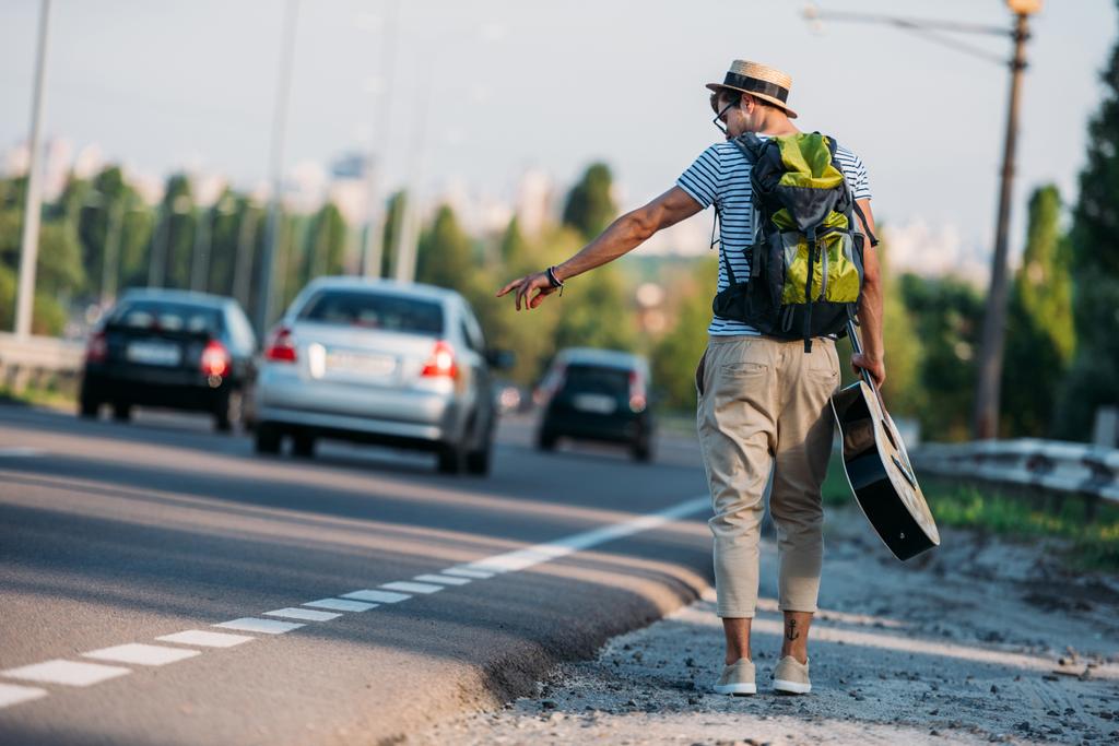 young man with guitar hitchhiking alone - Photo, Image