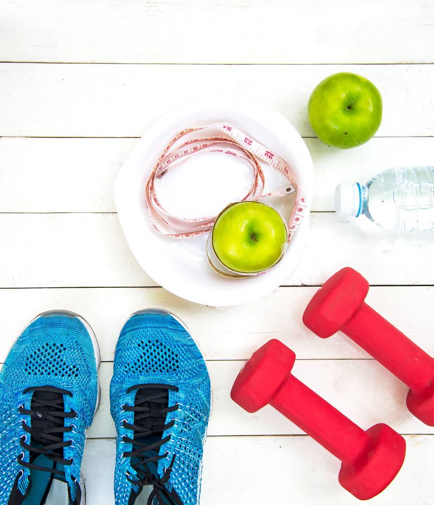 gesunder Lebensstil für Frauen Ernährung mit Sportgeräten, Turnschuhen, Maßband, Obst gesunde grüne Äpfel und eine Flasche Wasser auf Holz. Gesundes Konzept. - Foto, Bild