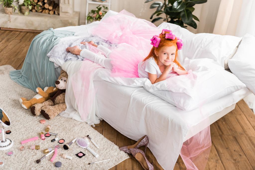 Pieni tyttö papiljotit lepää sängyllä
 - Valokuva, kuva