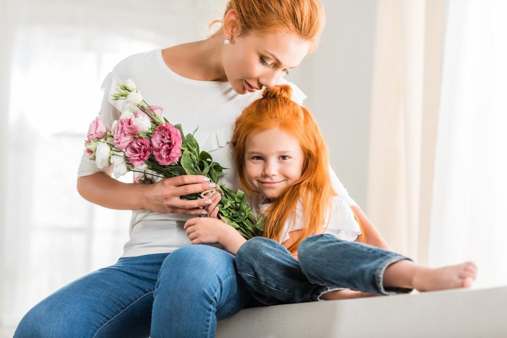 Mutter mit Blumen umarmt kleine Tochter - Foto, Bild