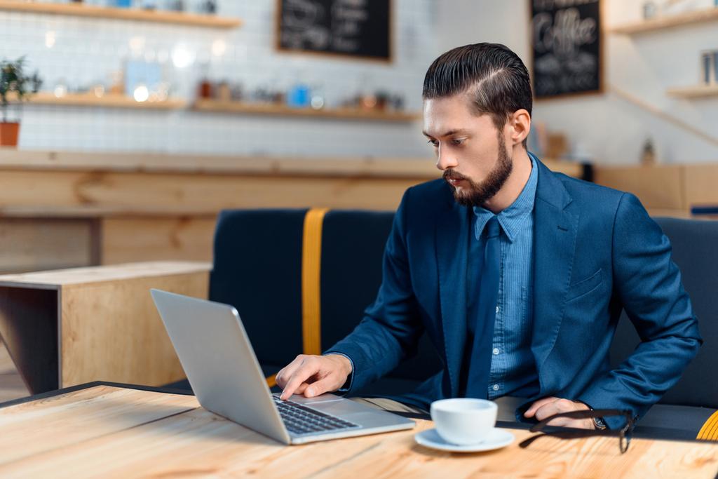 Empresario usando laptop en cafetería
 - Foto, imagen