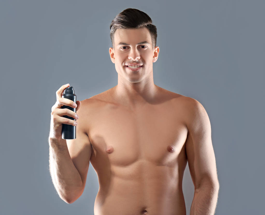 Csinos, fiatal férfi dezodor szürke háttér - Fotó, kép