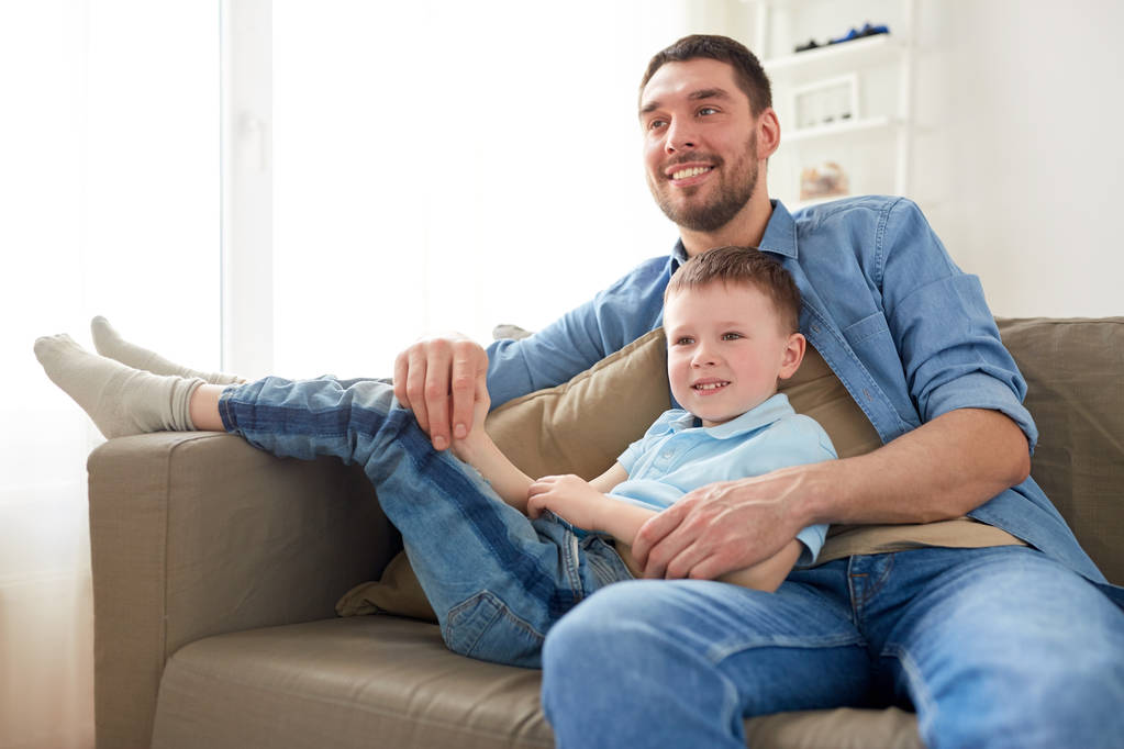 onnellinen isä ja poika istuu sohvalla kotona
 - Valokuva, kuva