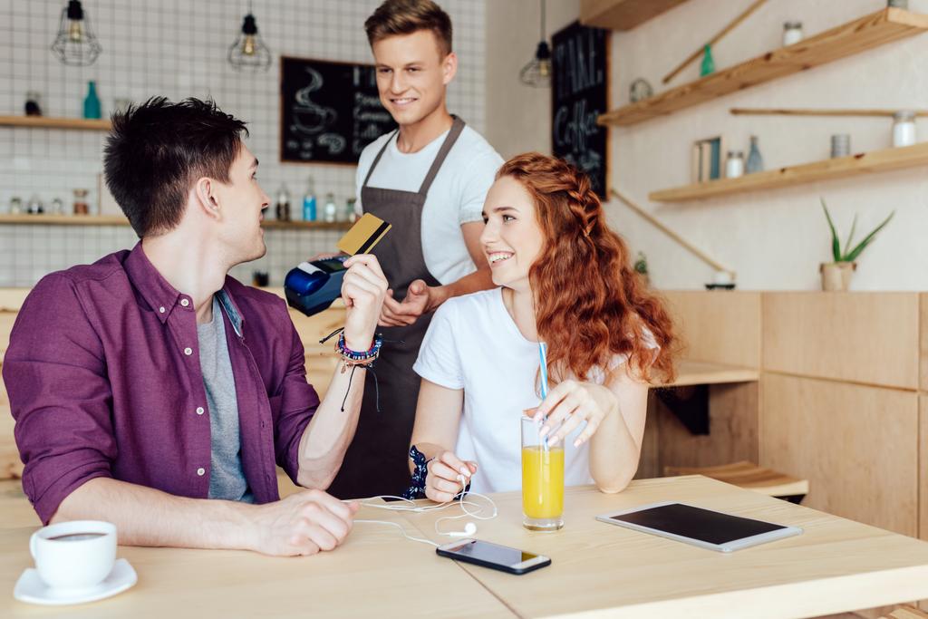 пара, платящая кредитной картой в кафе
 - Фото, изображение