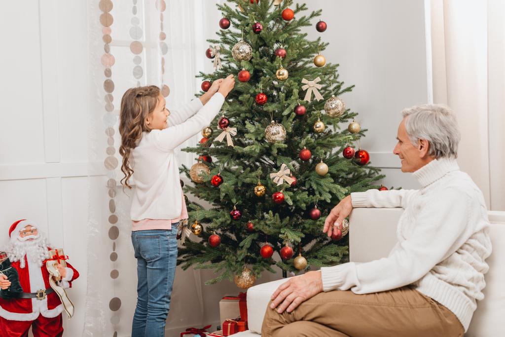 grand-père et petite-fille décorant l'arbre de Noël
 - Photo, image
