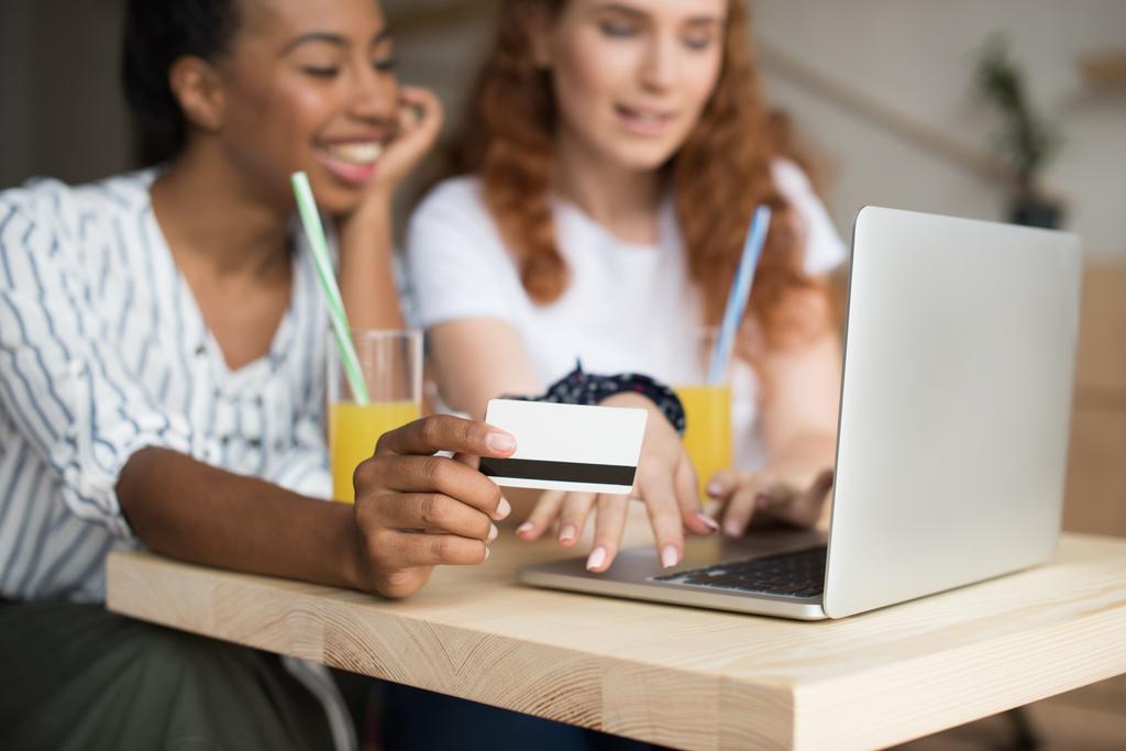 monikansalliset tytöt kannettavan tietokoneen ja luottokortin kanssa
  - Valokuva, kuva