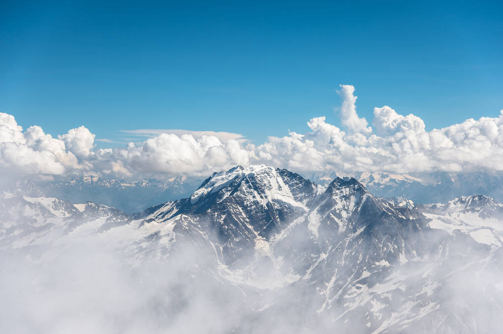 Ciel bleu foncé avec nuages sur les sommets rocheux des montagnes couvertes de glaciers et de neige
 - Photo, image