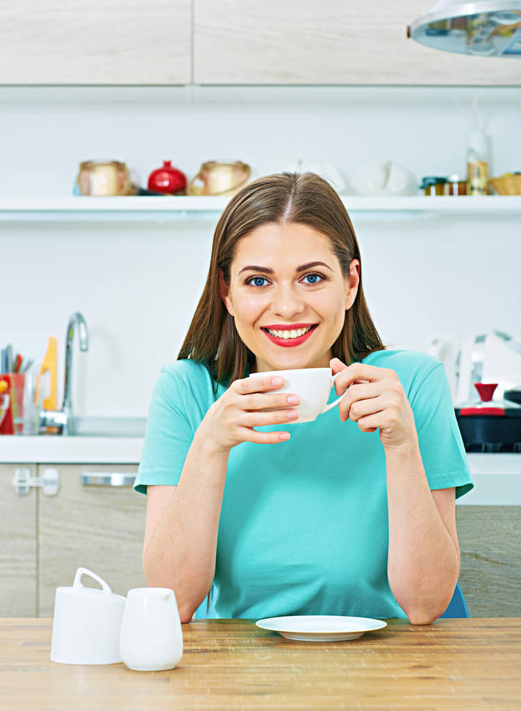 Frau sitzt mit Kaffeetasse in Küche  - Foto, Bild
